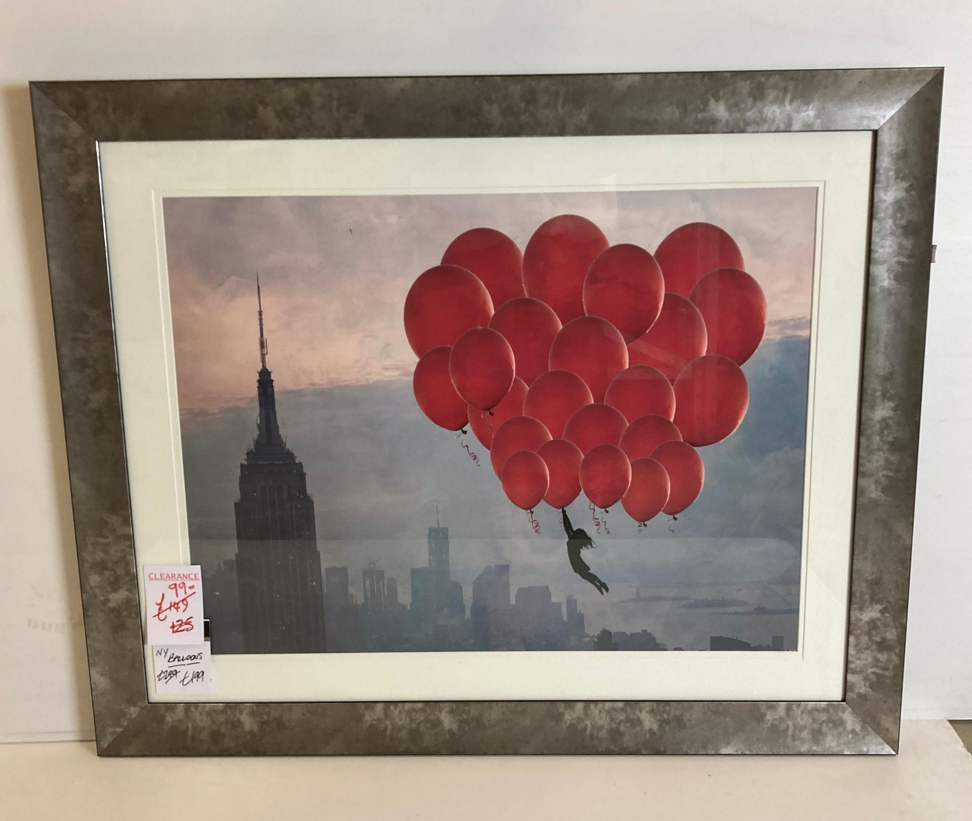 Print of New York balloons in dark wood frame,