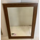 A rectangular wall mirror with oak-effect surround,