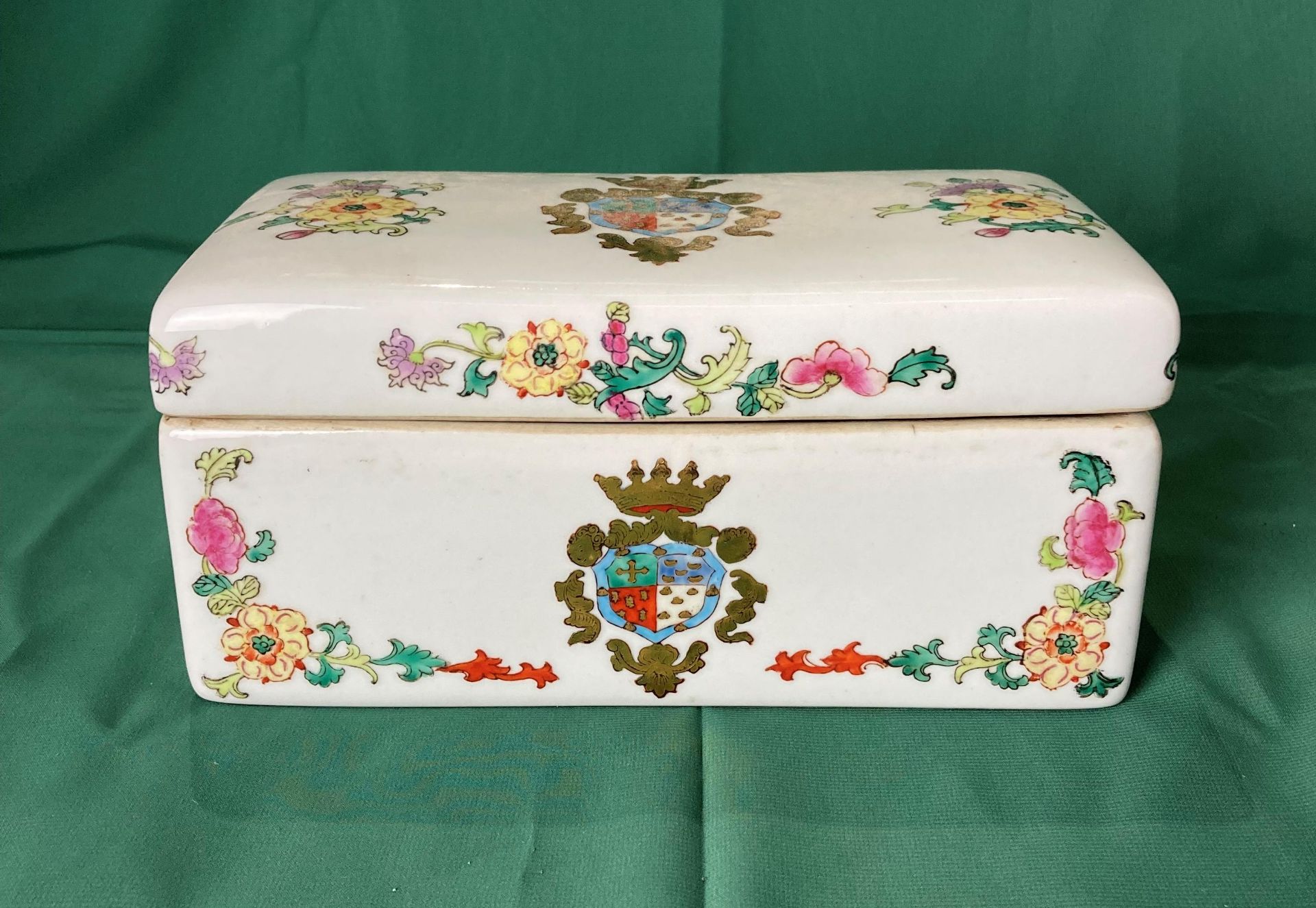 A vintage porcelain hand-painted box with Coat of Arms emblem and floral design,