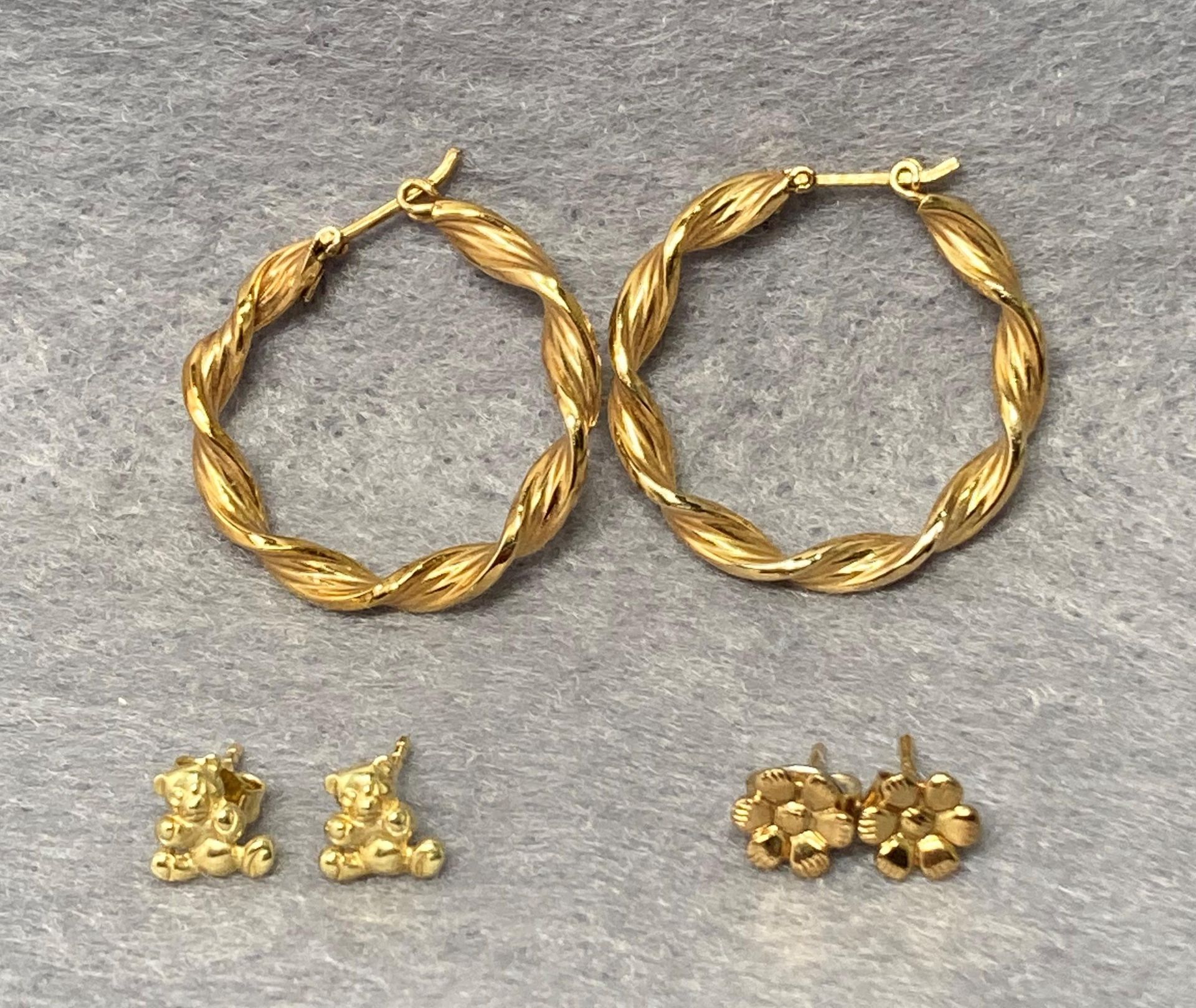 Two pairs of 9ct gold earrings - a twisted hoop pair and a flower stud pair together with a pair of
