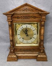 A vintage oak cased mantel clock with brass and gilt face with Roman numerals,