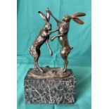 A bronze sculpture of two boxing hares on marble base by Mario Nick,