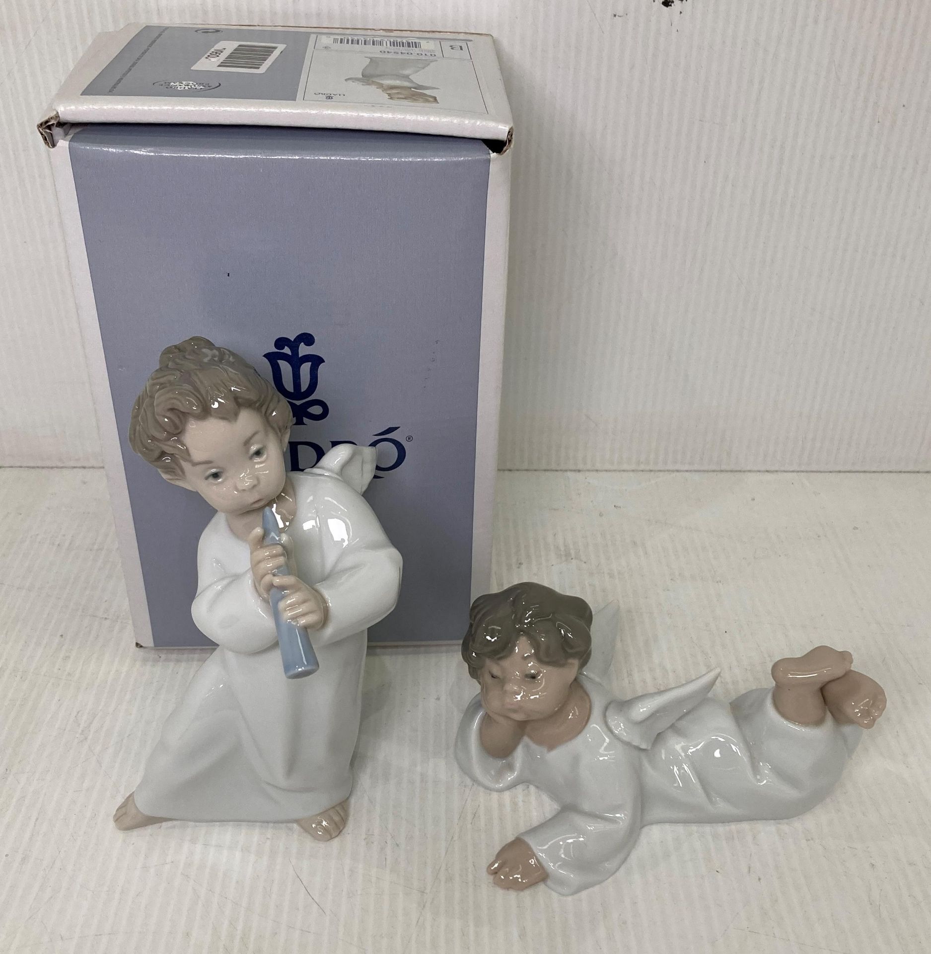 Two Lladro Angel figurines including Angel with Flute (with box - 16cm high) and a Laying Angel