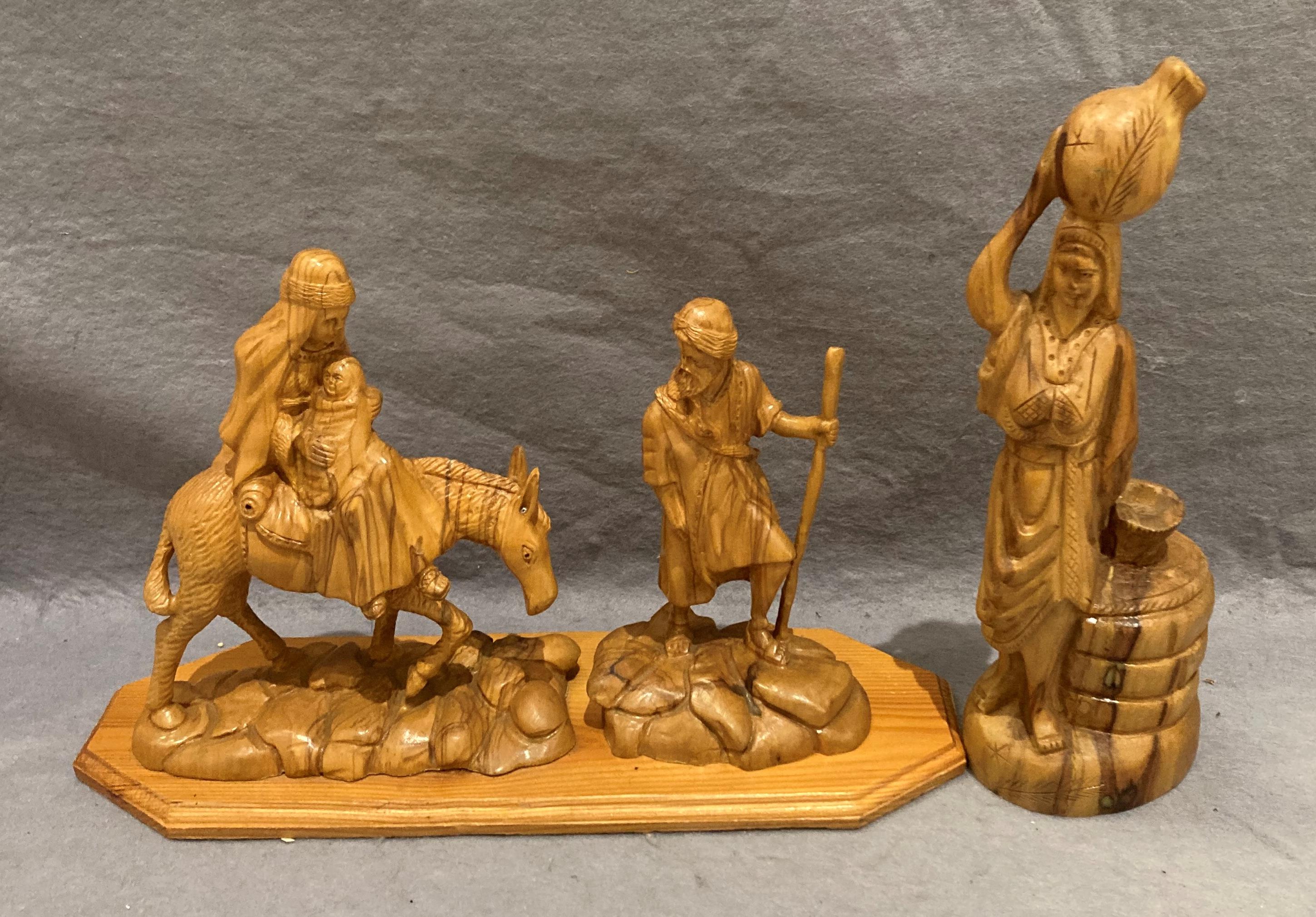 A hand-carved olive wood 'Flight to Egypt' religious carving on wooden plinth (35cm x 22cm high)