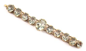 A 1920s style bracelet, with graduated pale blue oval glass beads, each in a rub over gold coloured