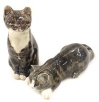 Two Mike Linton ceramic cats, comprising seated tabby with amber eyes, 20cm high, and pouncing tabby