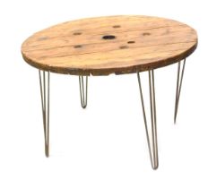 A rustic pine top circular garden table, with wrought iron legs, 120cm diameter.
