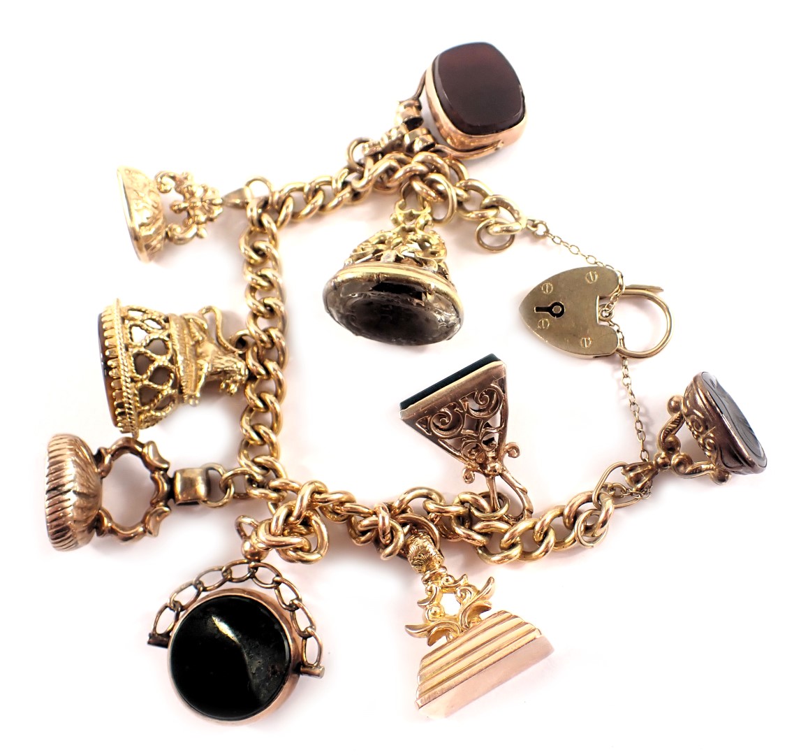 A 9ct gold charm bracelet, the curb link bracelet with heart shaped padlock and safety chain, applie