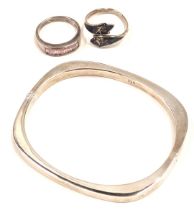 A shaped bangle, white metal stamped 925, and two white metal dress rings, one stone set, one of eas