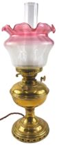 A brass oil lamp, the pink and white frosted shade decorated with flowers in Art Nouveau style, 50cm