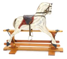 A dapple grey painted rocking horse, on a pine trestle base, 128cm long.