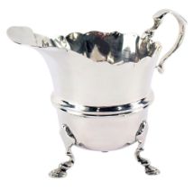 A George V silver cream jug, with a fluted border, on tripod feet, London 1924, 2oz.