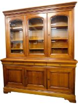 A French cherrywood bookcase, the top with a moulded cornice above three glazed doors enclosing adju