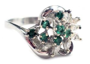 An emerald and diamond twist ring, set with seven round brilliant cut emeralds, each in four claw se