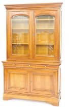 A French cherrywood bookcase, the top with a moulded cornice above two glazed doors enclosing adjust