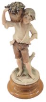 A Florence figure of a boy carrying grape vines, on circular wooden base, 30cm high.