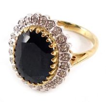 A 9ct gold cluster ring, the central oval black stone in rub over setting, surrounded by tiny diamon