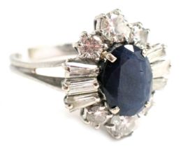 A sapphire and diamond cluster ring, the oval sapphire in claw setting, 9.4mm x 7.2mm x 3.4mm approx