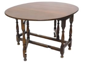 An oak oval drop leaf table, on turned supports, 113cm wide.