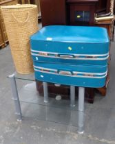 Two Revelation blue suitcases, wicker storage basket and three tier glass TV stand.