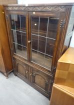 An oak two door display cabinet, with carved top rail above arrangement of two glazed doors and two
