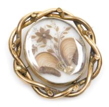 A Victorian memorial brooch, with central oval panel with locks of hair and flower type design, in a