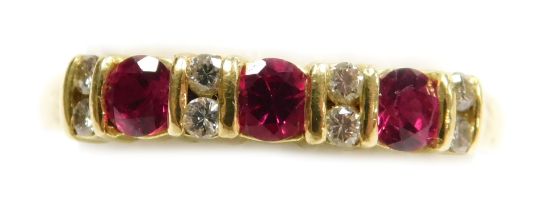 An 18ct gold and ruby three stone ring, set with pairs of diamonds at intervals, size N, 2.7g.