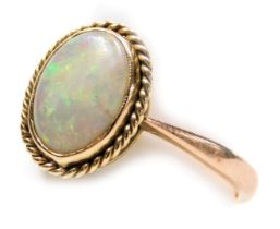 A 9ct gold and opal single stone ring, in an oval setting with a rope twist surround, size Q, 3.1g.