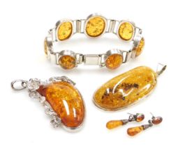 A group of silver and amber jewellery, comprising a silver and amber pendant, 7cm high, another in s