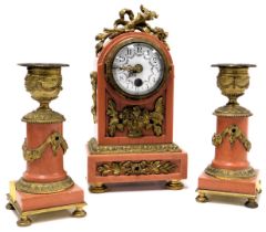 A French Louis XVI style pink marble boudoir garniture, comprising a clock with circular enamel dial