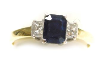 An 18ct gold sapphire and diamond three stone ring, the rectangular cut sapphire flanked by a pair o