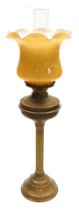 A brass oil lamp, with an amber colour glass shade and glass chimney, converted to electricity, 70cm