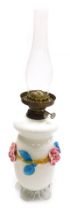 A 20thC milk glass oil lamp, with shaped body raised with glass flowers on a shaped base with plain