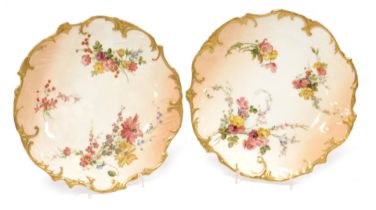 A pair of Royal Worcester blush ivory porcelain cabinet plates, decorated with flowers, etc., within