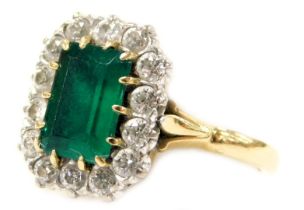 An 18ct gold emerald and diamond ring, the rectangular cut emerald in a surround of brilliant cut di