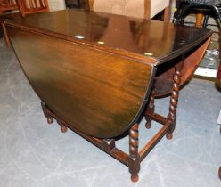 An oval oak gate leg drop leaf dining table, raised on barley twist supports.