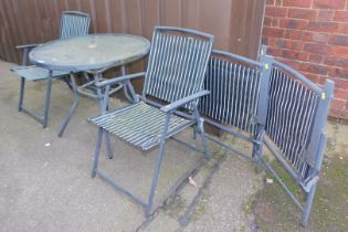 A circular glass topped garden table and four garden chairs.