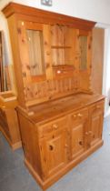 A pine dresser with two glazed doors with single drawer between, two shelves over a base unit of thr