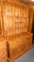 A pine dresser, with plate rack over two doors, over three drawers above three doors raised, on plin