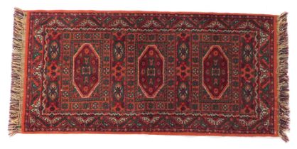A Persian rug, red ground, decorated centrally with medallions within multiple borders, 140cm x 70cm