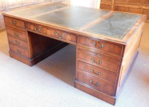 A 20thC yew partner's desk, the top with three green gilt tooled leather insets, with a moulded edge