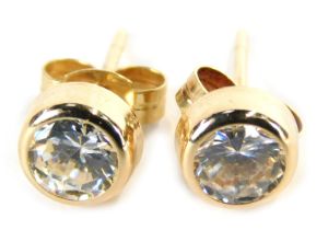 A pair of stud earrings, each with imitation diamond, in a rub over setting on single pin back with