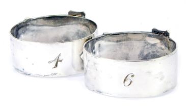 Two George V napkin rings, of buckle and strap oval form, numbered 4 E-9, silver plated, bearing ini