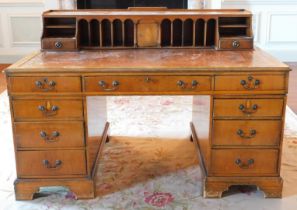 A 20thC yew desk, the raised top with an arrangement of recesses, central cupboard and drawers, etc.