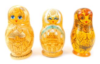 Three Russian Matryoshka nesting dolls, each decorated centrally with a depiction of a Russian Ortho