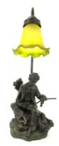 A 20thC table lamp, with frosted yellow and green trumpet glass shade above a figure of a young man