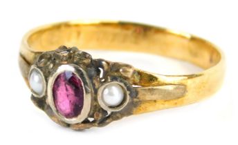 A Victoria dress ring, set with oval cut garnet in white metal rub over setting, flanked by t