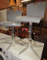 A pair of swivel bar stools, each with grey leatherette padded seat and back.