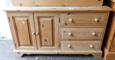 A pine side cabinet, the top with moulded edge, above two panelled cupboards, flanked by three drawe