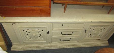 A painted hardwood side cabinet, with three drawers flanked by two carved pierced doors, on a steppe